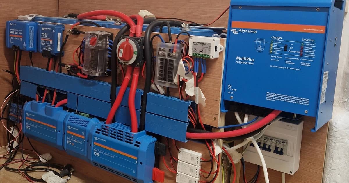 Victron omvormer/lader, zonneladers en stroomrails gemonteerd op de wand van een camper