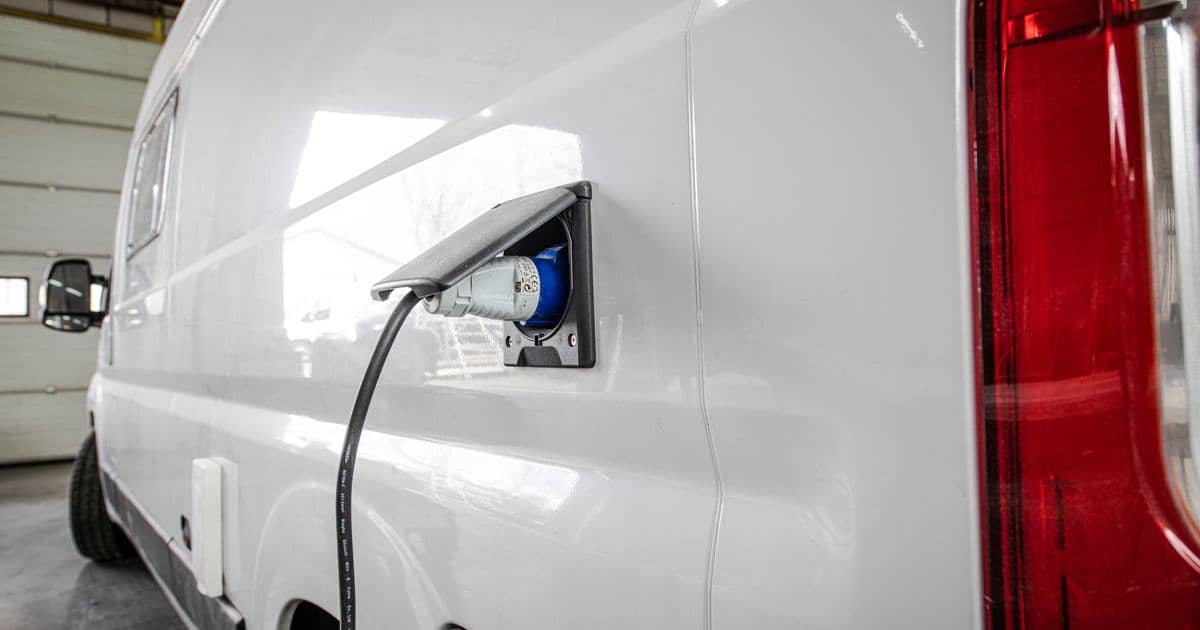 Walstroomkabel aangesloten op het aansluitpunt aan de zijkant van een kampeerauto